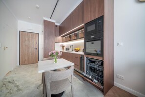 Une cuisine moderne avec des meubles en bois, un plan de travail blanc et des appareils électroménagers intégrés, notamment un four à micro-ondes et un four traditionnel.