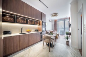 A modern kitchen with wooden cabinets, a built-in oven, and a dining area with a table and chairs. - Chmielna Duo Exclusive | Warsaw Center & Parking (Warszawa)