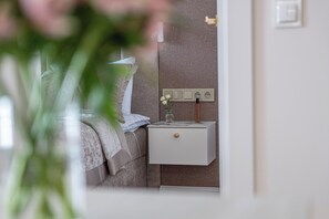 Ein Schlafzimmer mit einem Bett, einem Nachttisch mit einer Vase und einer Wandsteckdose.