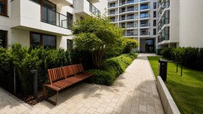 Un bâtiment moderne doté d’un chemin, d’un banc et d’un espace vert bien entretenu.