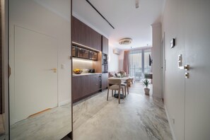A modern kitchen with dark wood cabinets, a dining area with a table and chairs, and a large window with curtains. - Chmielna Duo Exclusive | Warsaw Center & Parking (Warszawa)