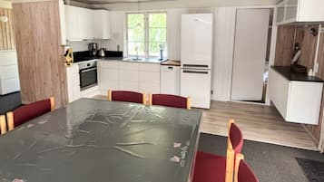 A modern kitchen with white cabinets, a dining table with chairs, and a refrigerator.