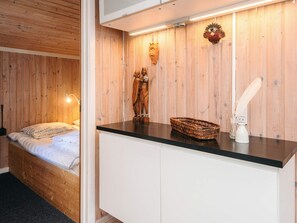 A room with a bed, a wooden wall, a white cabinet, a woven basket, and a wall-mounted light fixture. - 8 Person Holiday Home in Farvang (Farvang)