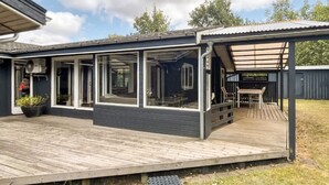 Ein modernes Haus mit überdachter Terrasse und großen Fenstern.