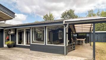 A modern house with a covered deck and large windows.