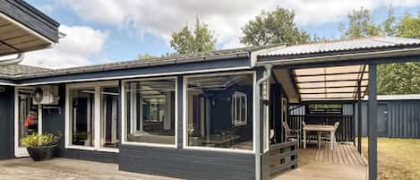 A modern house with a covered deck and large windows.