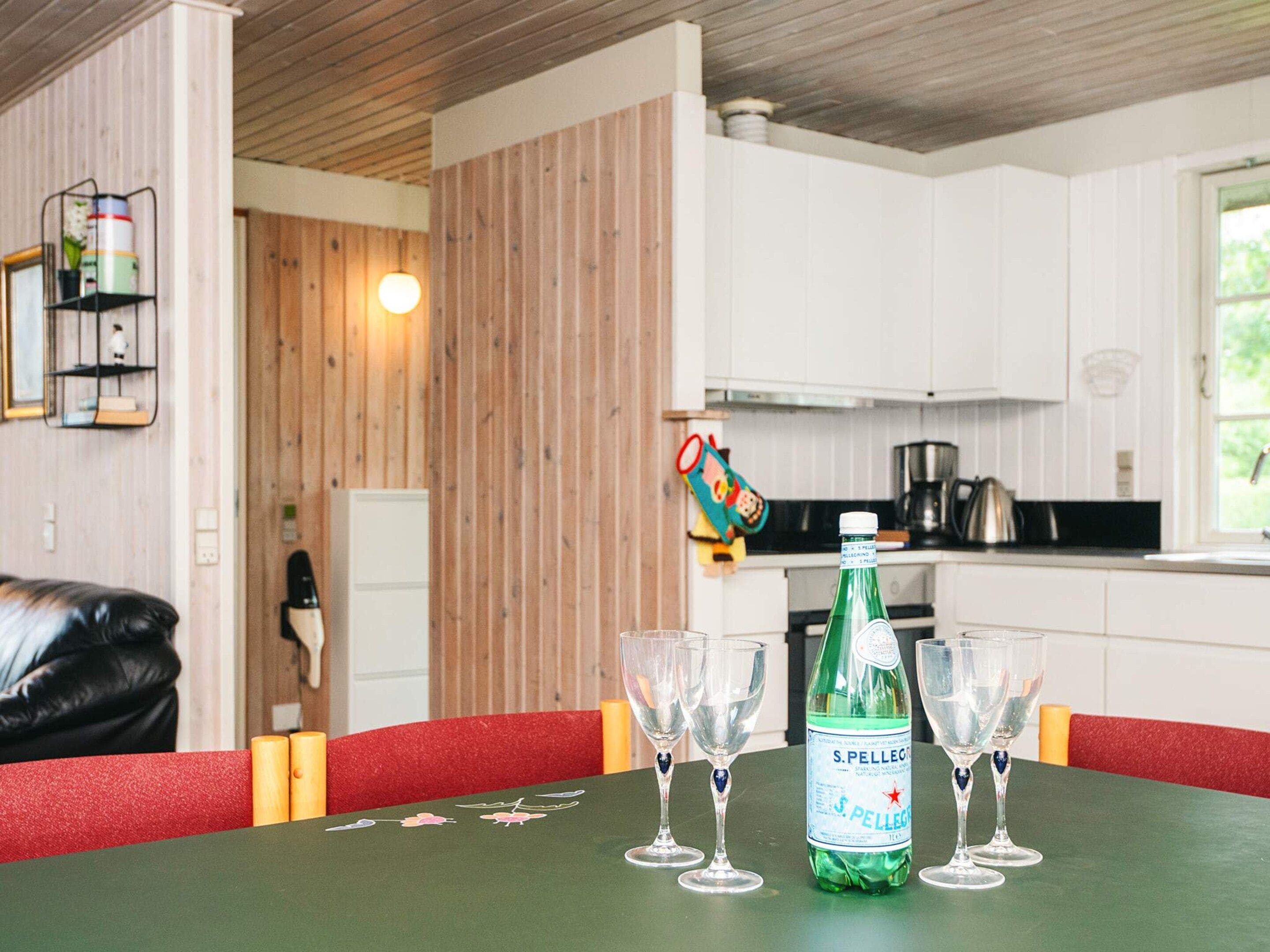 Een eettafel met een fles S. Pellegrino bruisend water en vier glazen.