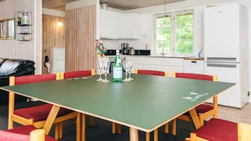 Ein Essbereich mit einem grünen Tisch, roten Stühlen und einer Küche im Hintergrund.
