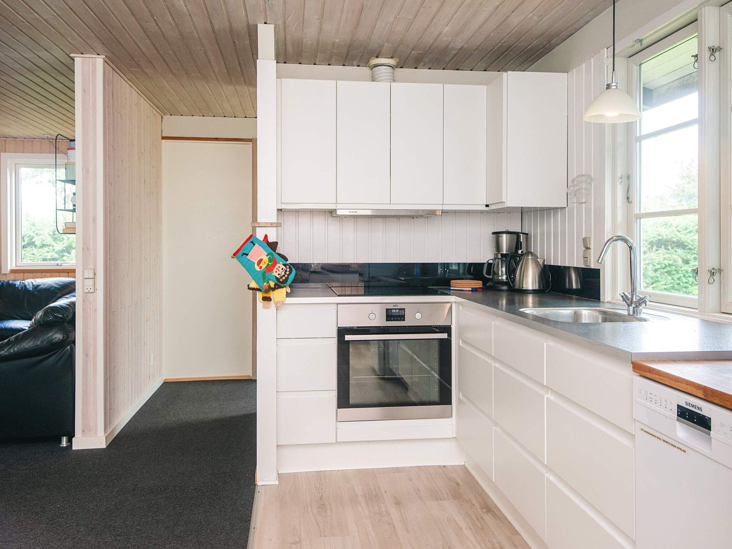 Een moderne keuken met witte kasten, een inbouwoven en een Siemens vaatwasser.