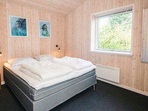 Une chambre à coucher avec un lit, deux lampes fixées au mur, une fenêtre et deux tableaux encadrés.