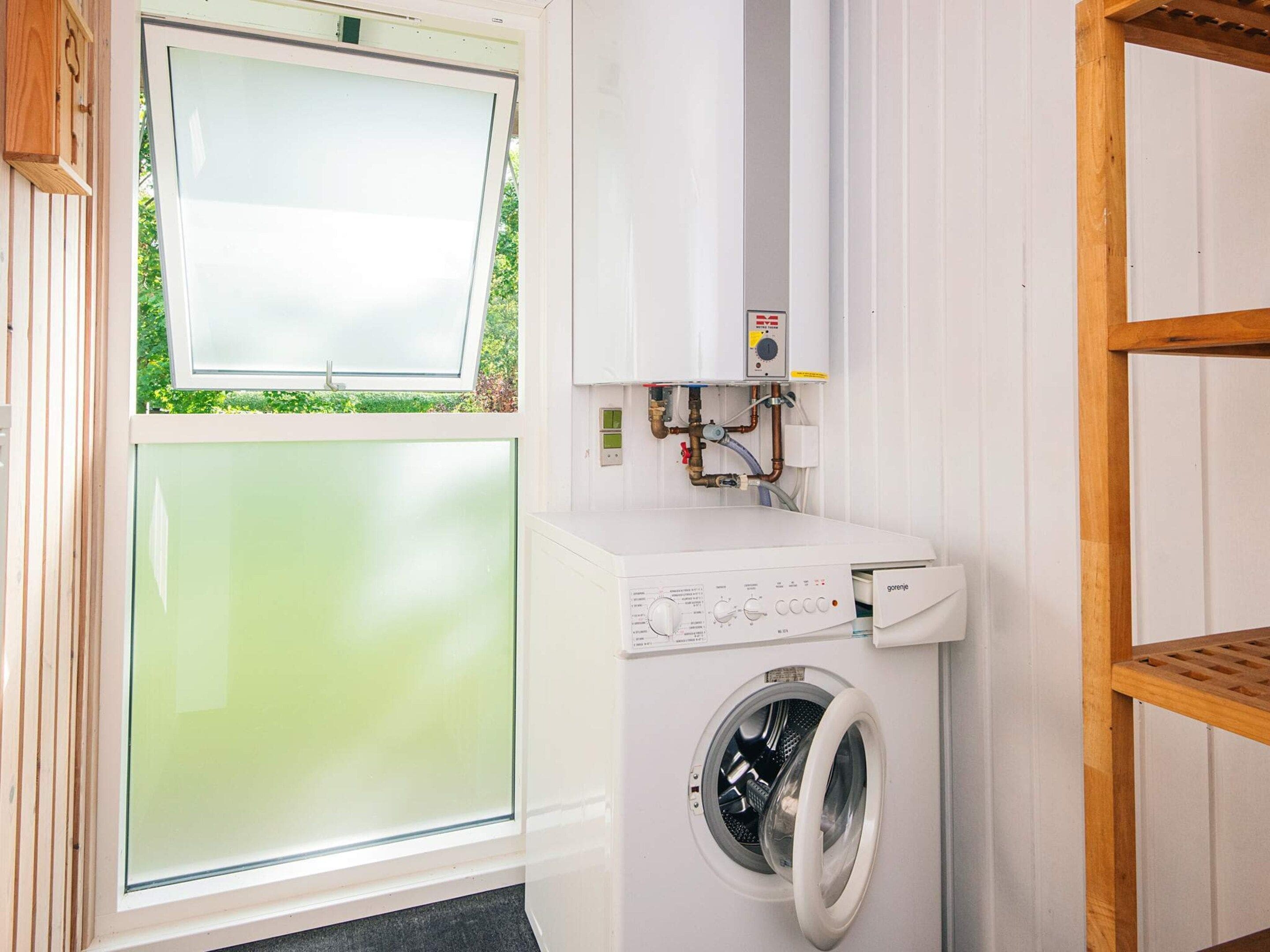 Een wasserette met een voorlader wasmachine en droger, een raam en een houten plank.