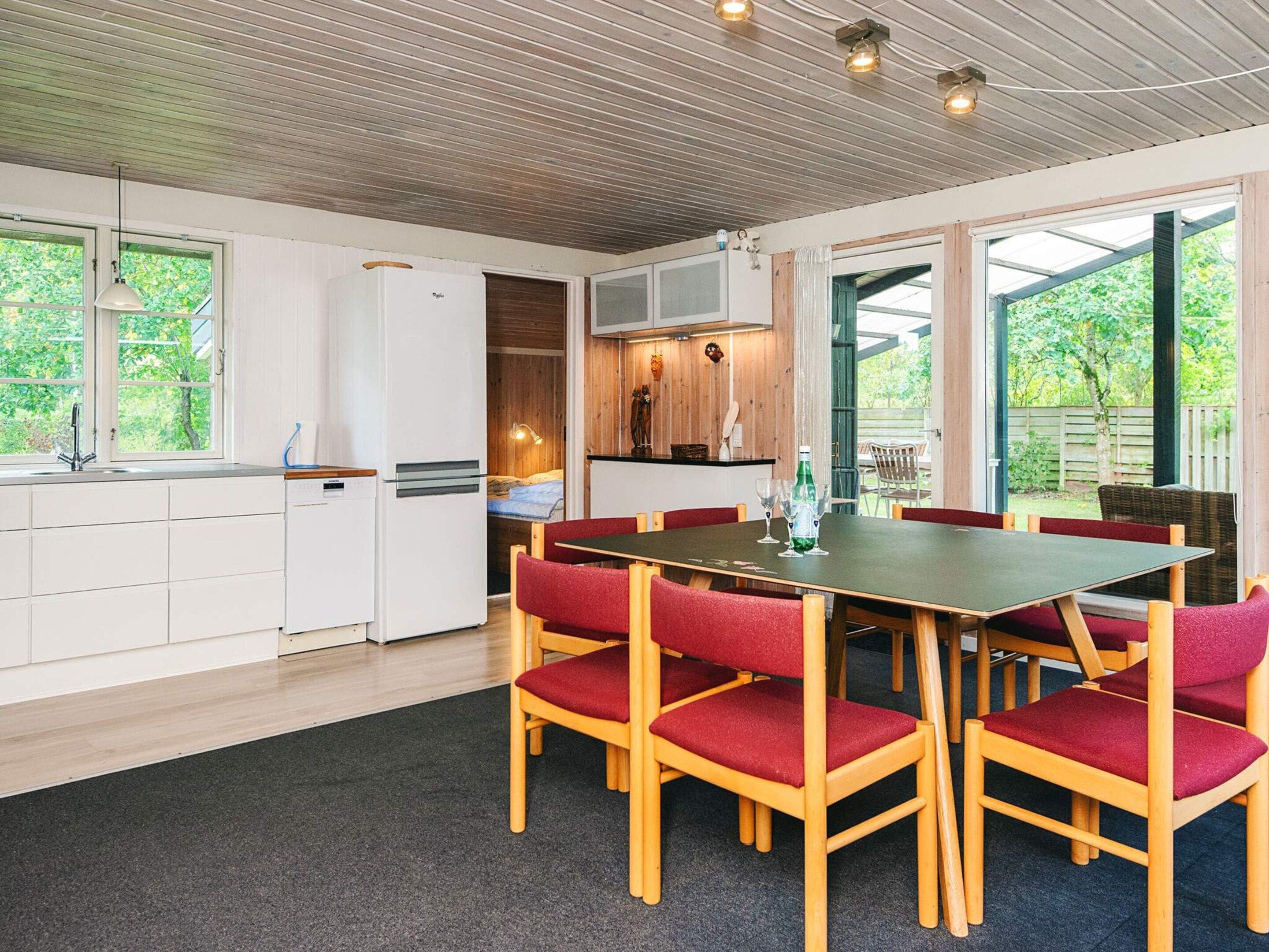 A modern kitchen with white cabinets, a built-in refrigerator, and a dining area with a table and chairs.