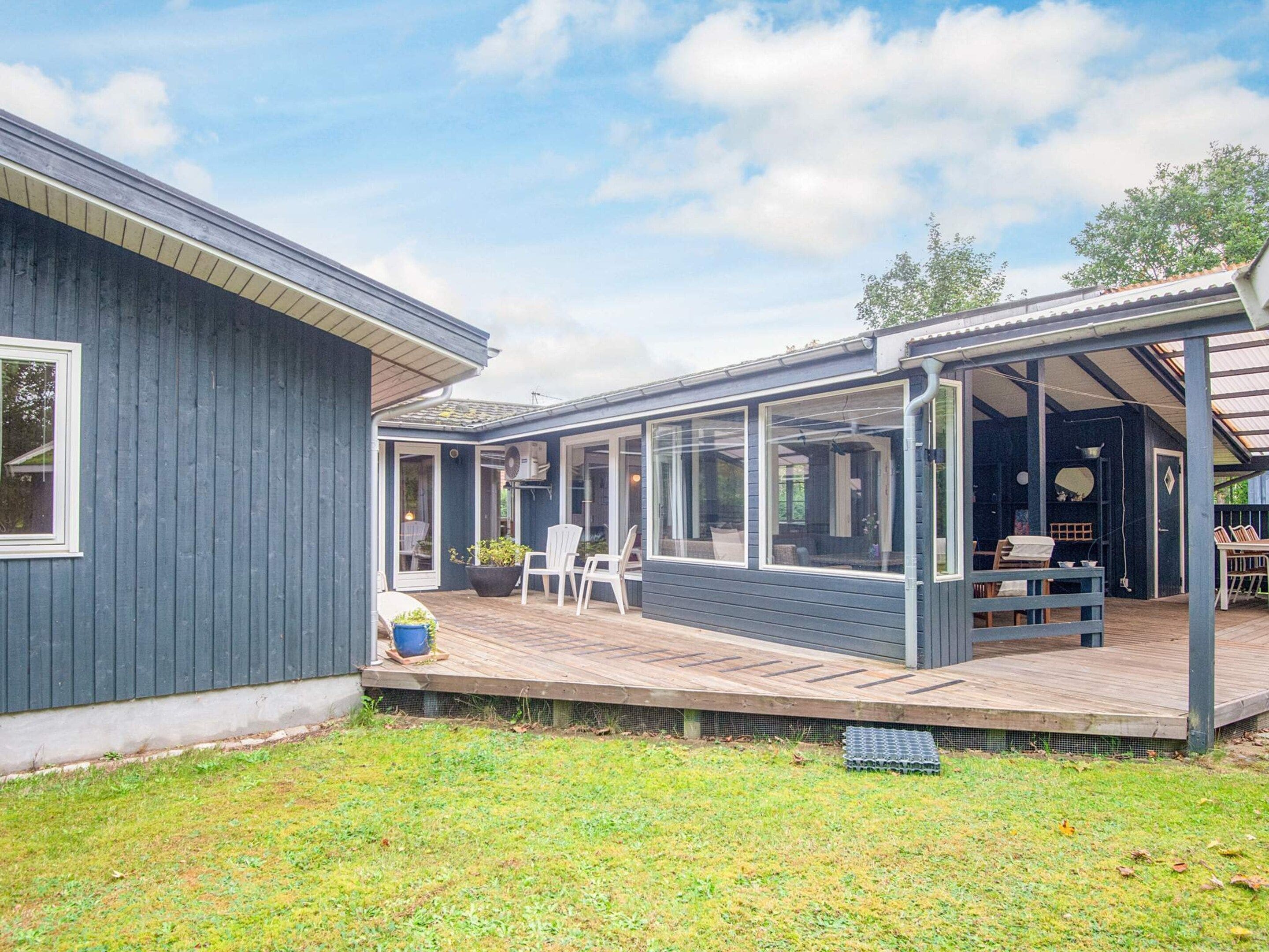 A blue house with a covered patio area, a small garden, and a clear sky.