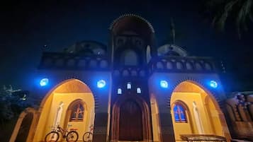 Een gebouw met boogvormige ingangen en een centrale toegang, verlicht met blauw licht.
