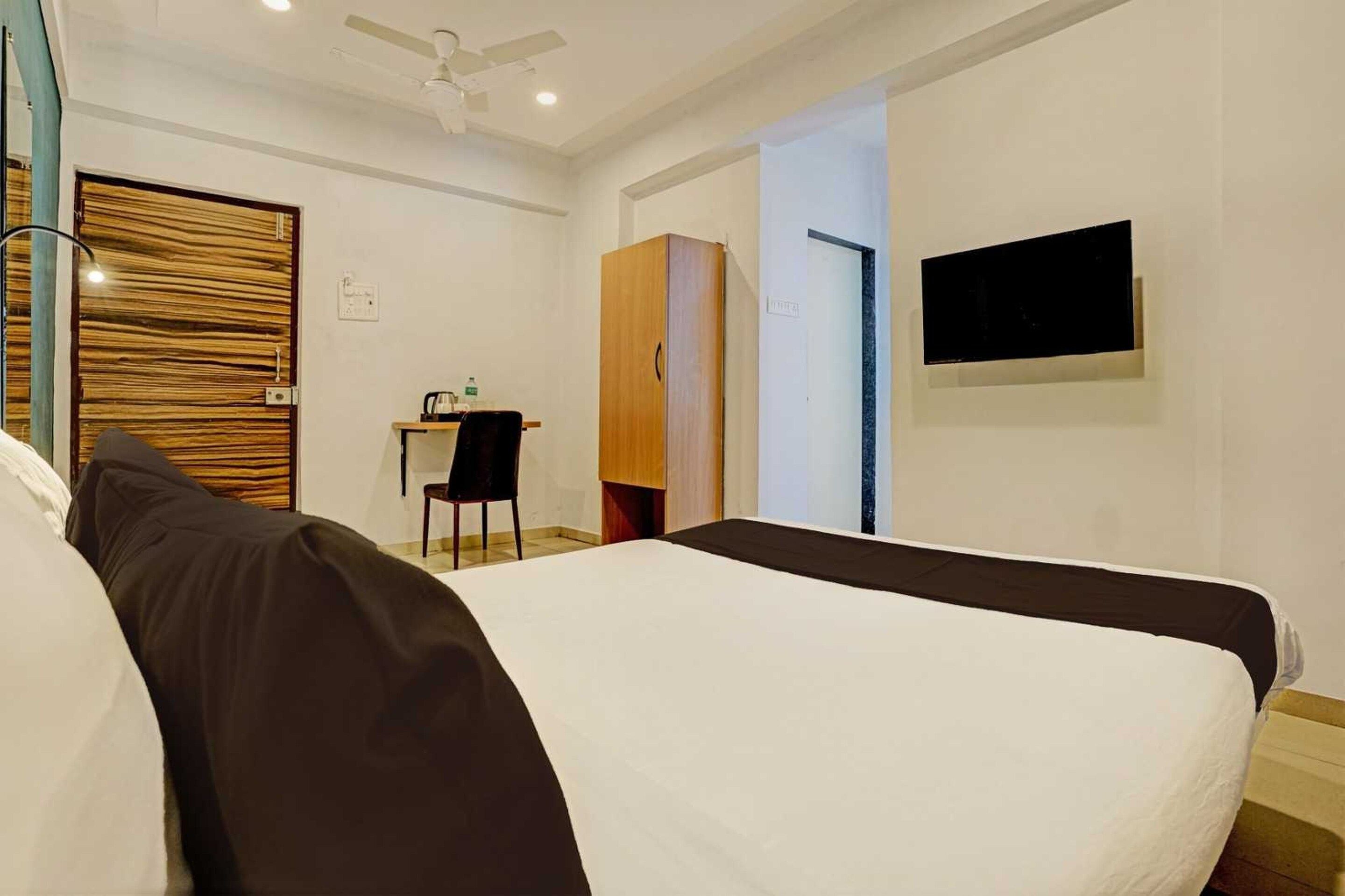 A hotel room with two beds, a desk, a chair, a wardrobe, and a TV on the wall.
