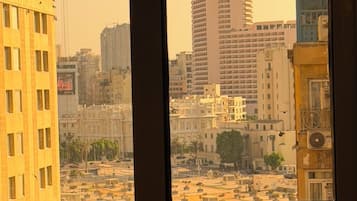 Vista per una finestra d'un paisatge urbà amb diversos edificis, incloent un gratacels i diverses construccions de mitjana alçada.
