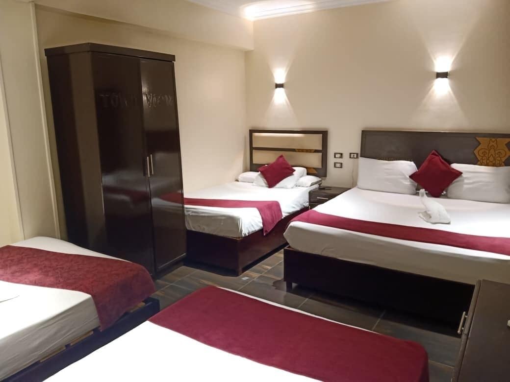 Habitació d'hotel amb dos llits, un armari i una tauleta de nit.