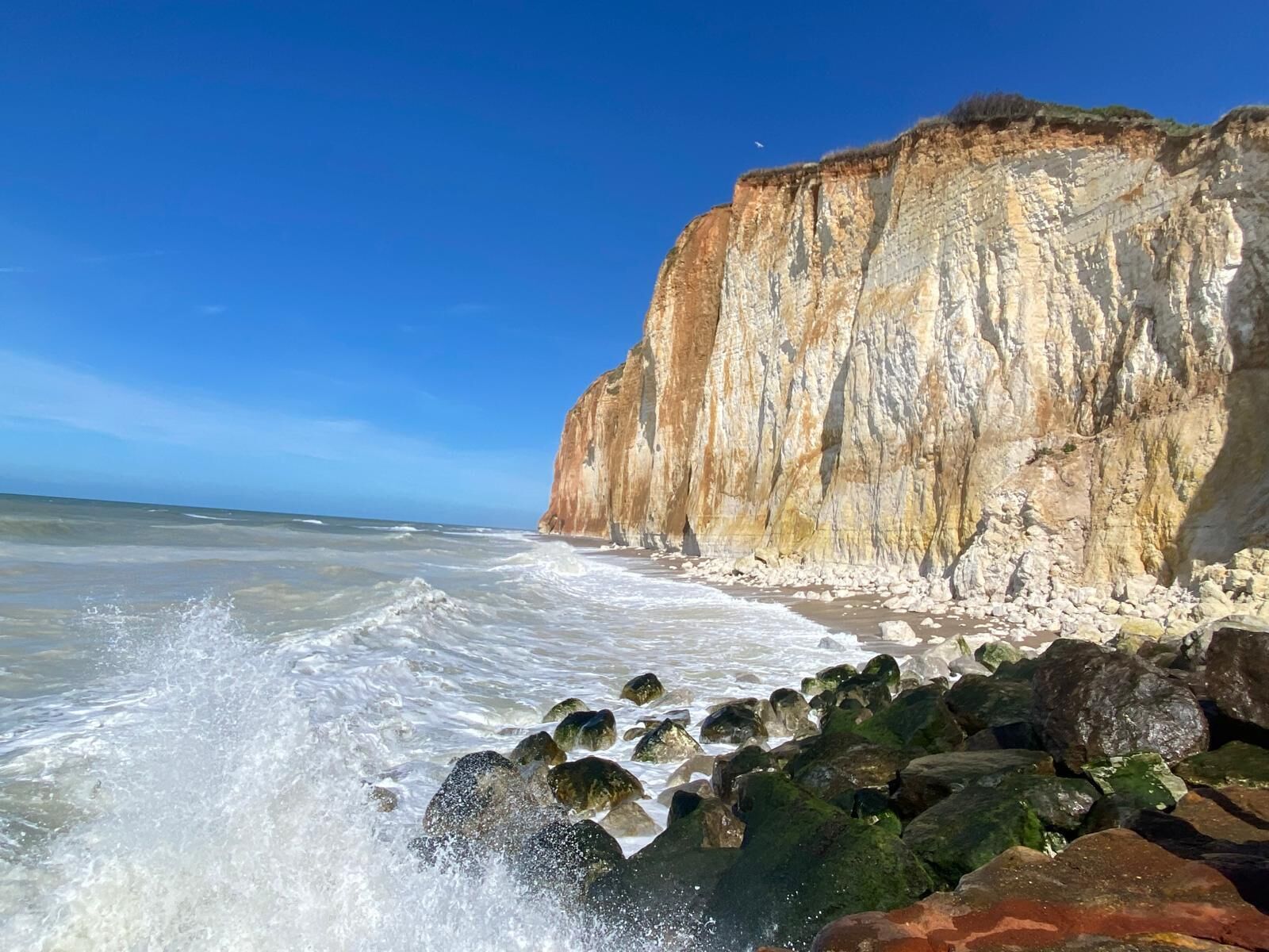 A coastal landscape with a prominent cliff and rocky shoreline.