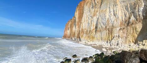 A coastal landscape with a prominent cliff and rocky shoreline.