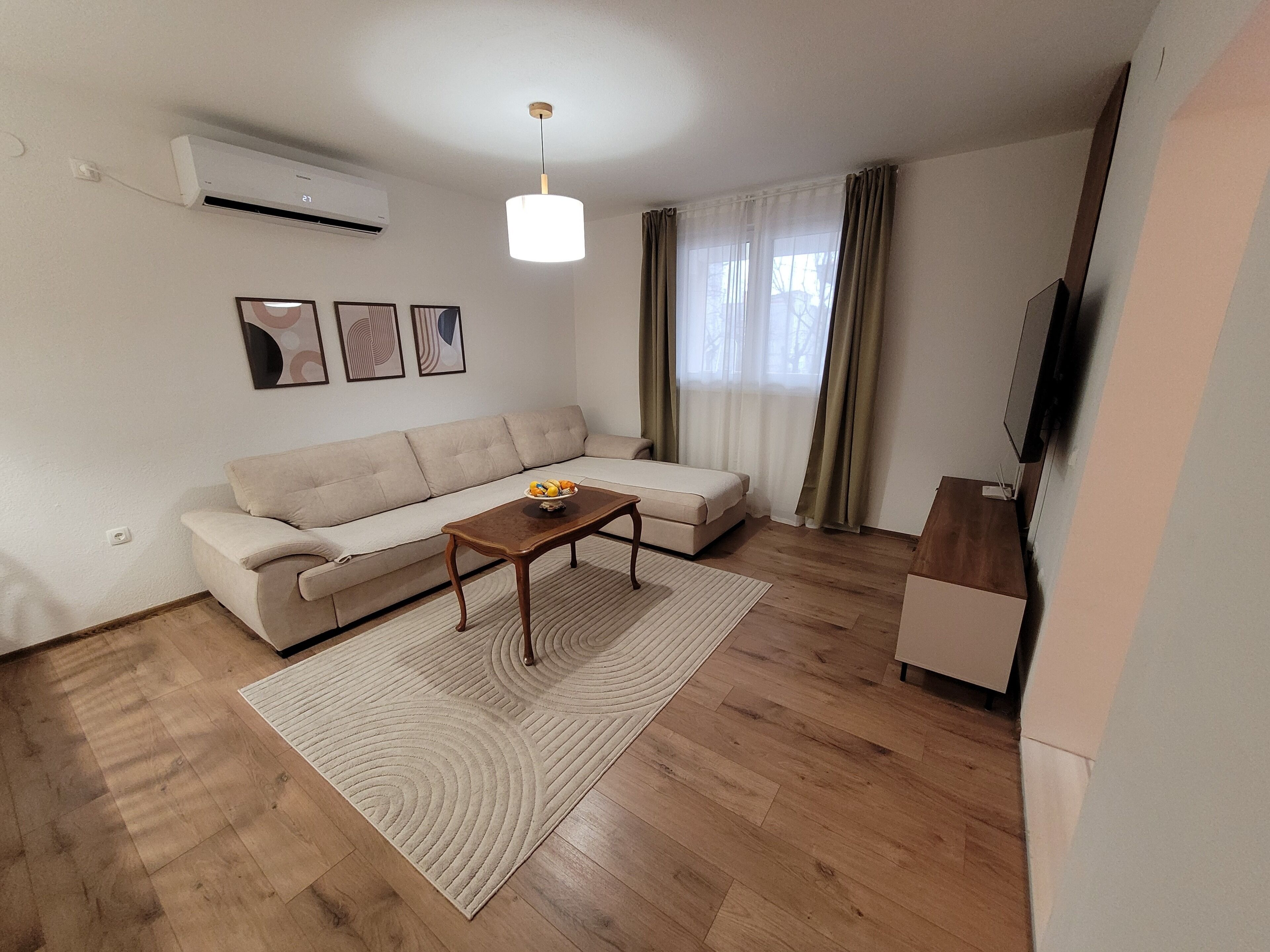 A modern living room with a sofa, a coffee table, and a television.