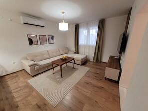 A modern living room with a sofa, a coffee table, and a television. - Apartment Holiday 
Self check-in FREE parking (Mostar)