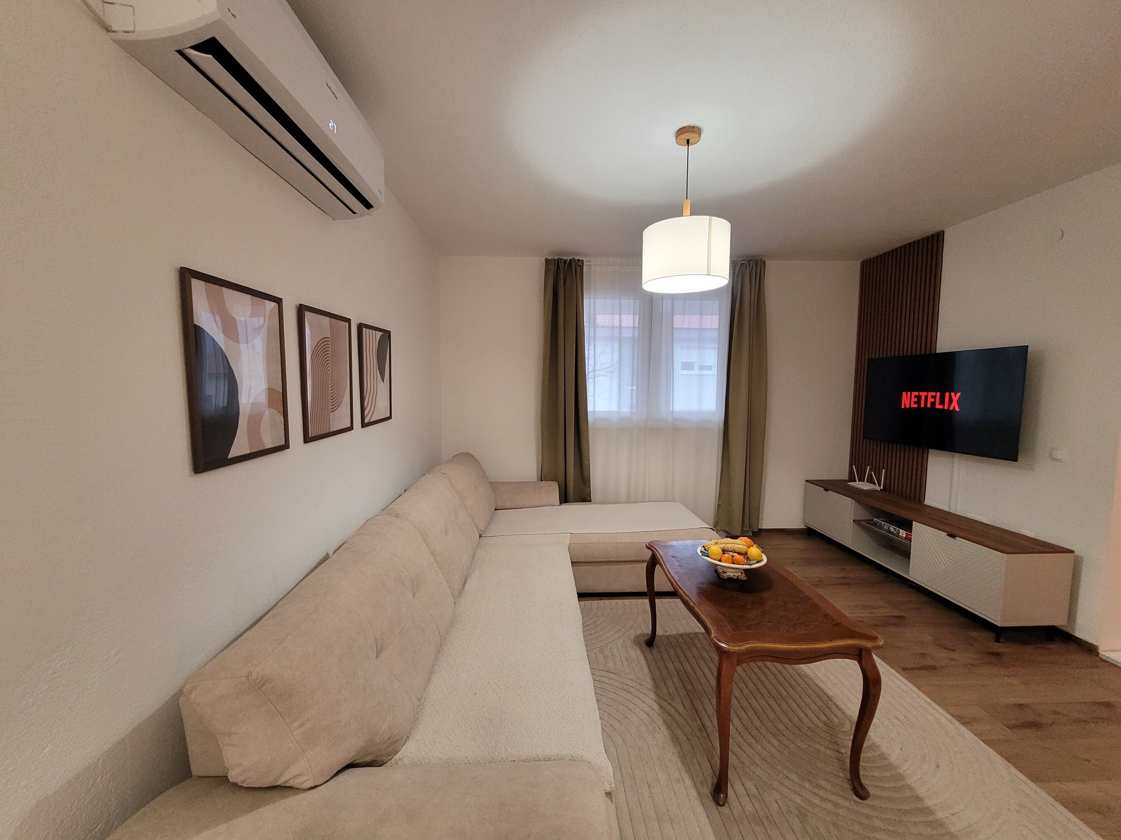 Ein Wohnzimmer mit einer Couch, einem Couchtisch, einem Fernseher und gerahmten Bildern an der Wand.