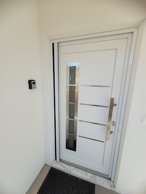 A white door with a frosted glass panel, a keyhole, and a doorbell.