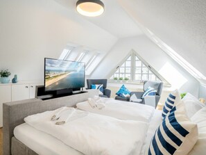 A modern bedroom with a large bed, a flat-screen TV, and a view of the sea through a skylight. - Holiday Apartment With 1 Bedroom (Heringsdorf)