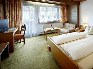 A hotel room with a bed, a desk, a chair, a sofa, and a TV. - Rettenstein Suite - Kaserer Country Inn (Bramberg am Wildkogel)