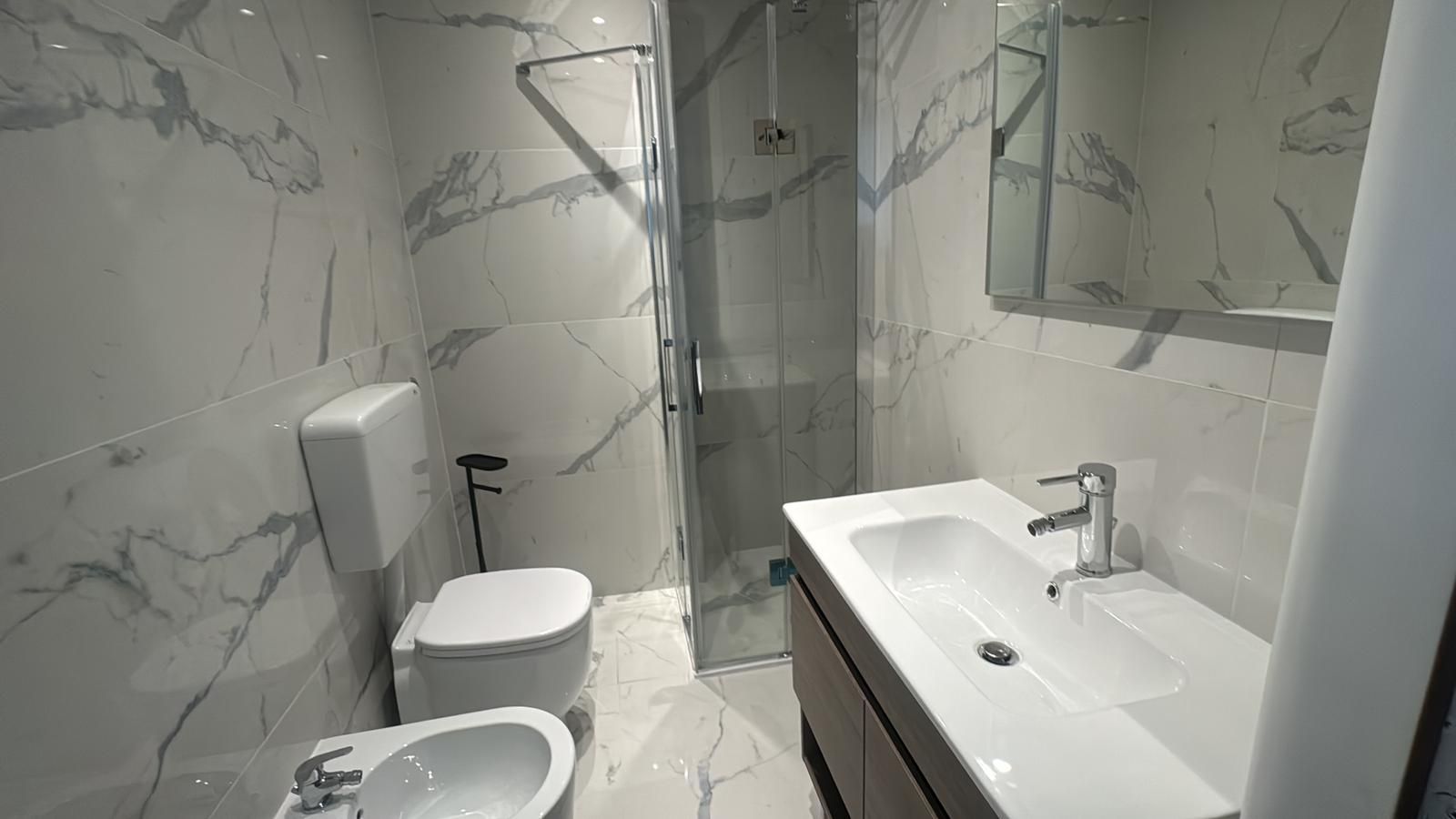 Een moderne badkamer met toilet, hygiëneschuimer en een groot wastafel.