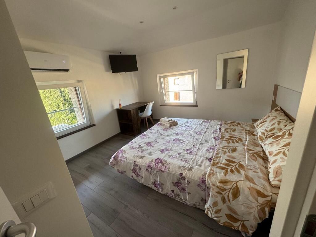 A bedroom with a bed, a desk, a chair, and a window.