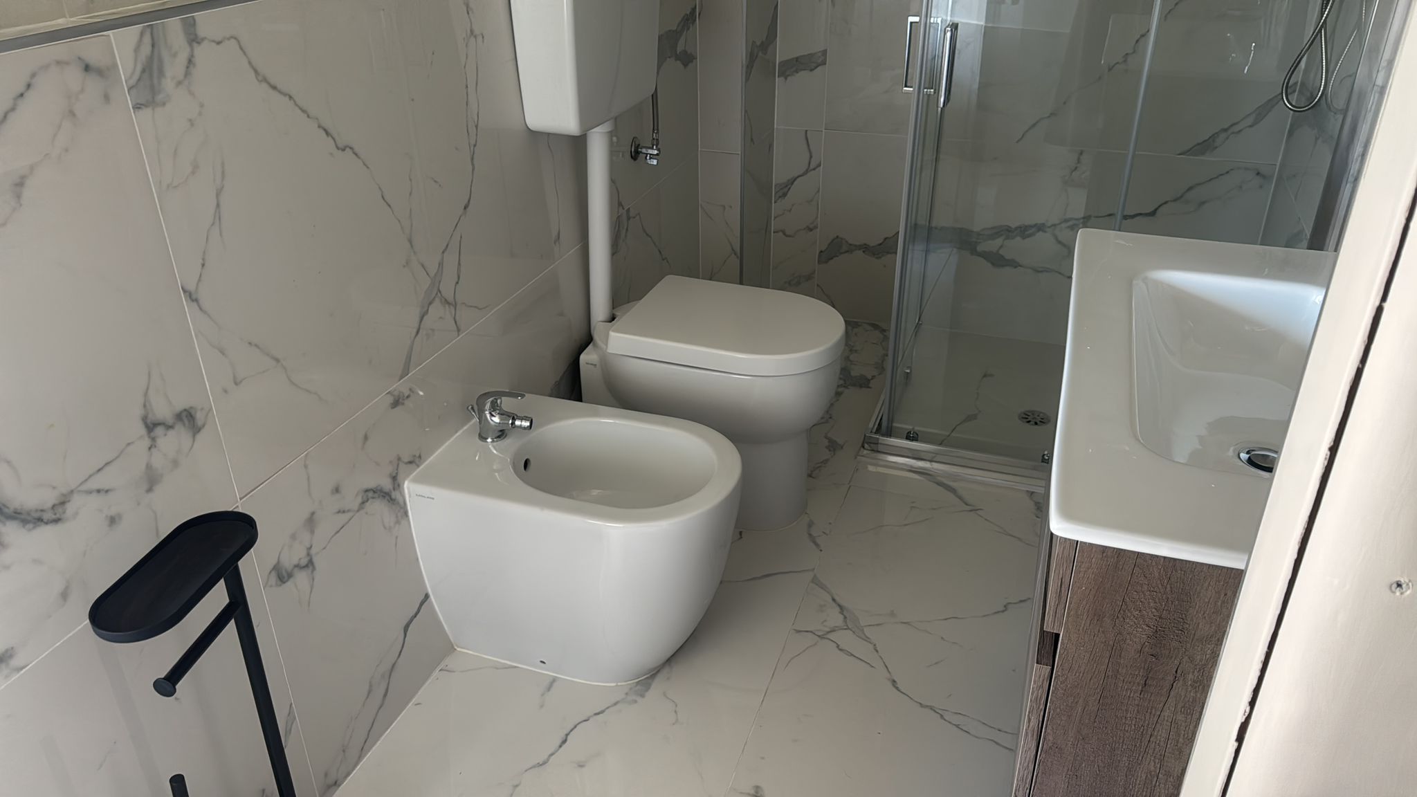 Un bagno con bidet, water, doccia e lavabo.