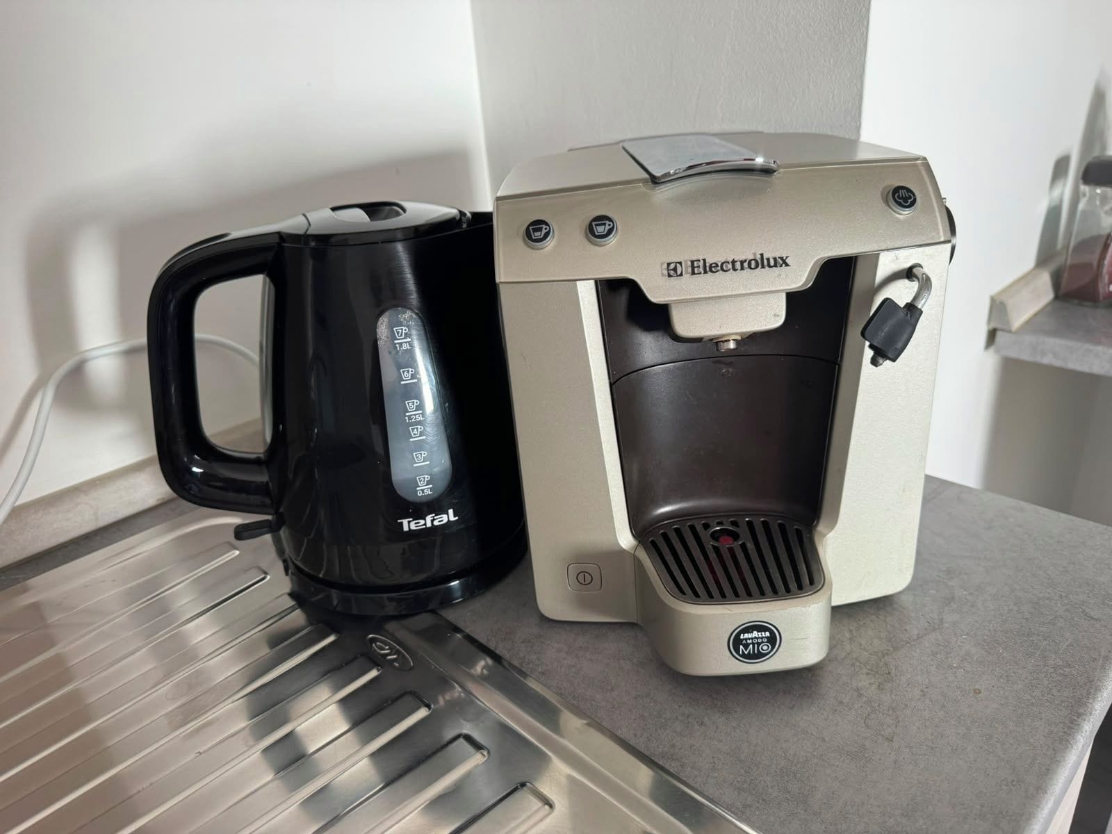 Une machine à café et une bouilloire sont posées sur un plan de travail.