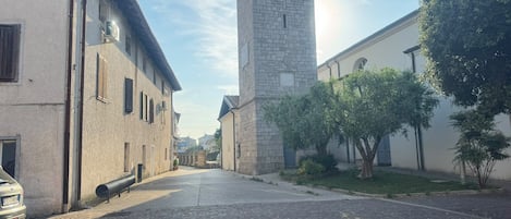 Una calle con edificios, una torre del reloj y árboles.