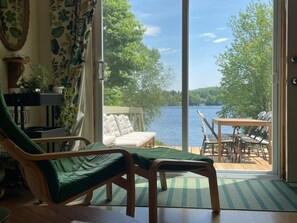 Quarto com vista para um lago, uma cadeira verde, um sofá branco e uma mesa com cadeiras.