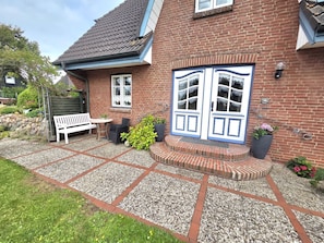 A brick house with a white bench, a small table, and a potted plant. - Tewelken Apartment - Tewelken Apartment in Wrixum - quiet location, modern (Wrixum)