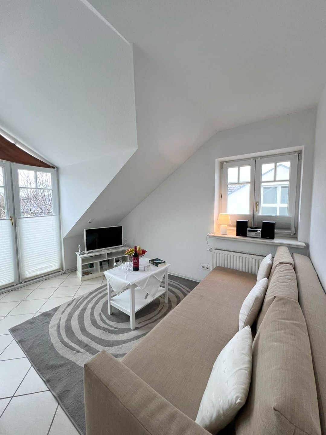Ein modernes Wohnzimmer mit Sofa, Couchtisch, Fernseher und Essbereich mit Tisch und Stühlen.