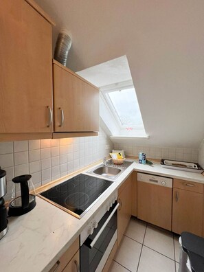 A compact kitchen with a skylight, a dishwasher, and a stove. - Leyla OG - Leyla Vacation Rental on Sylt: Balcony, Parking, and Dog-Friendly (Sylt)