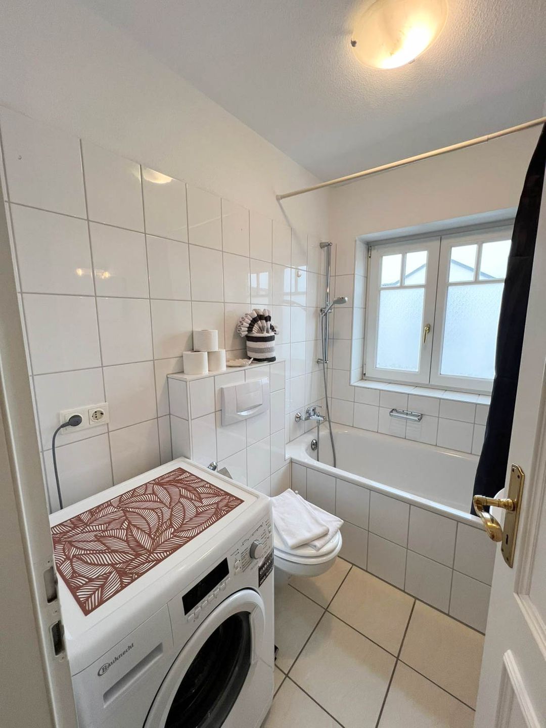 Ein kleines Badezimmer mit Waschmaschine, Toilette und Dusche.