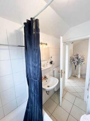 A bathroom with a white sink, a mirror, and a shower curtain. - Leyla OG - Leyla Vacation Rental on Sylt: Balcony, Parking, and Dog-Friendly (Sylt)