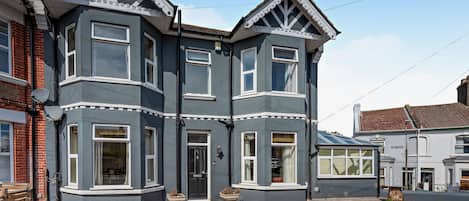 A two-story house with a bay window, a front door, and a small porch area.