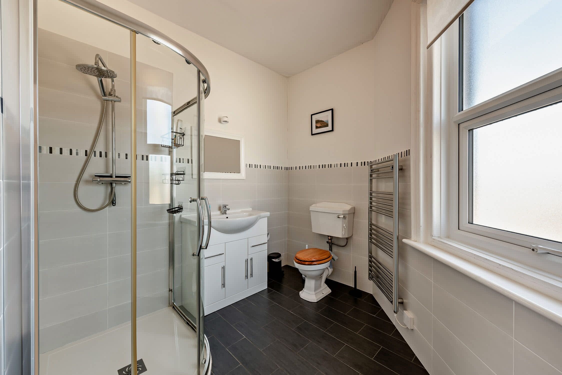 A modern bathroom with a glass-enclosed shower, a white sink, and a toilet.