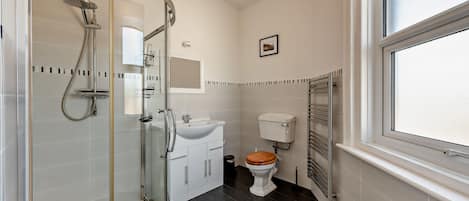 Een moderne badkamer met een glazen douchecabine, een wit wastafelmeubel en een toilet.