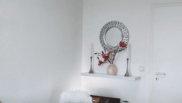 Ein Zimmer mit einem Glastisch, einer weißen Tür und einem dekorativen Spiegel an der Wand.