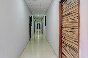 Un largo pasillo estrecho con piso de baldosas y puertas a ambos lados.