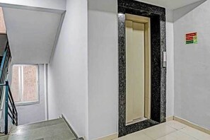 Un pasillo con una puerta que da a una habitación, una ventana y un cartel en la pared.