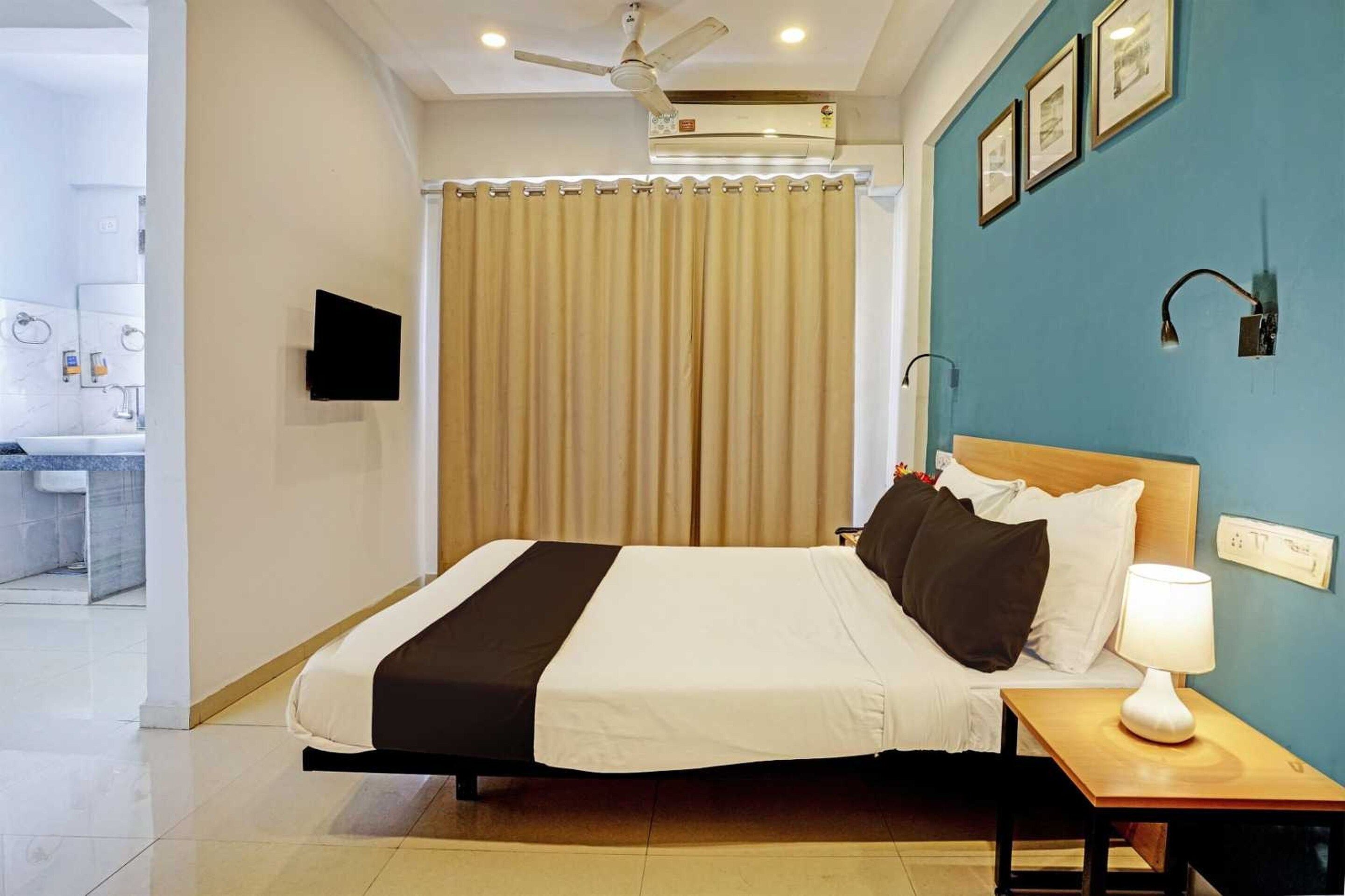 Une chambre d’hôtel avec un lit, une table de chevet, une lampe et une salle de bain visible au fond.