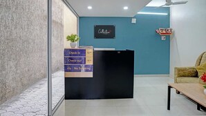 A reception desk with a sign indicating check-in and check-out times, a no-smoking sign, and a logo for 'Collection'. - Deluxe Bhumi Stay inn (Bhiwandi)