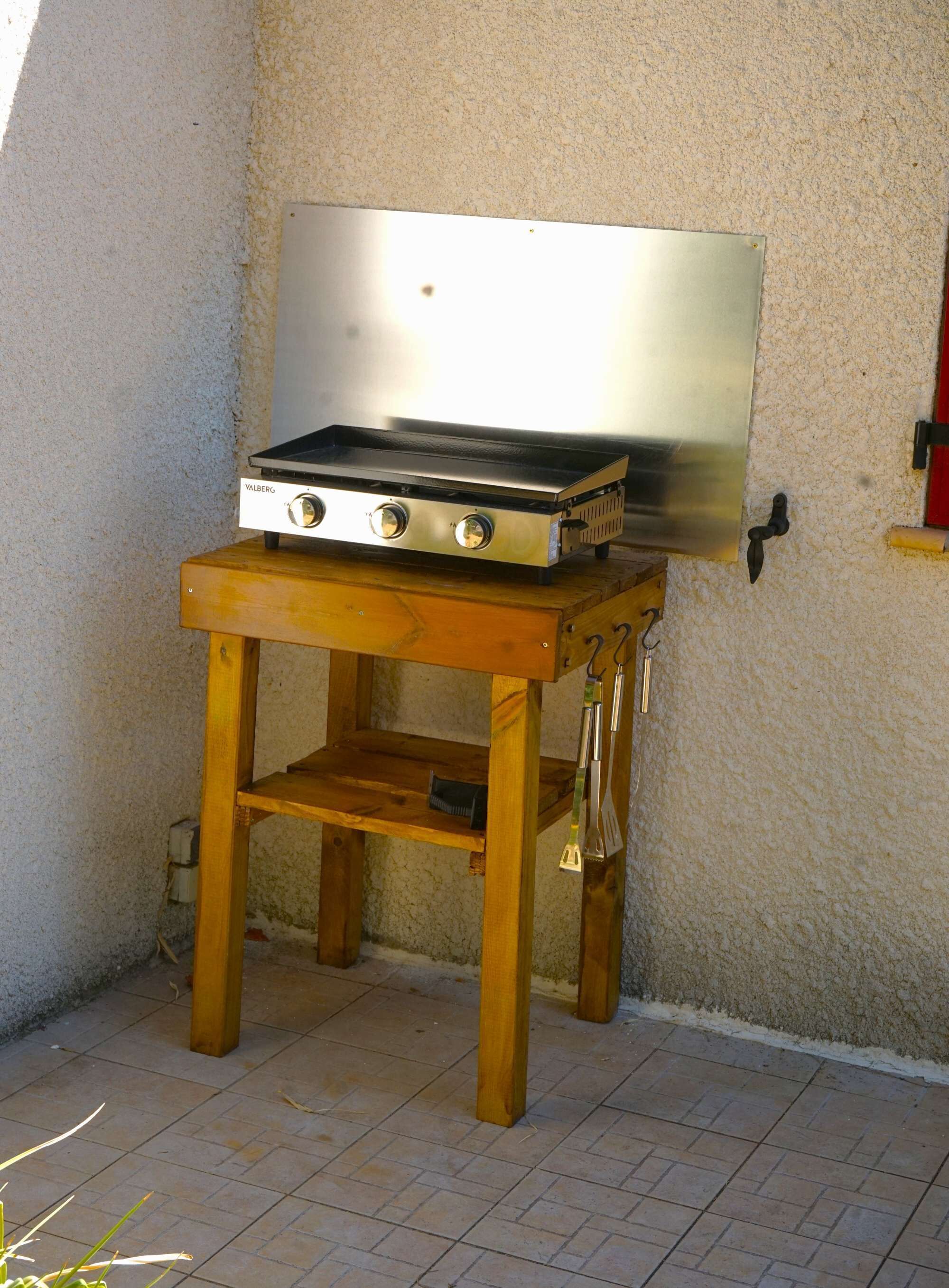 Estufa de gas portátil con tres quemadores sobre un soporte de madera.