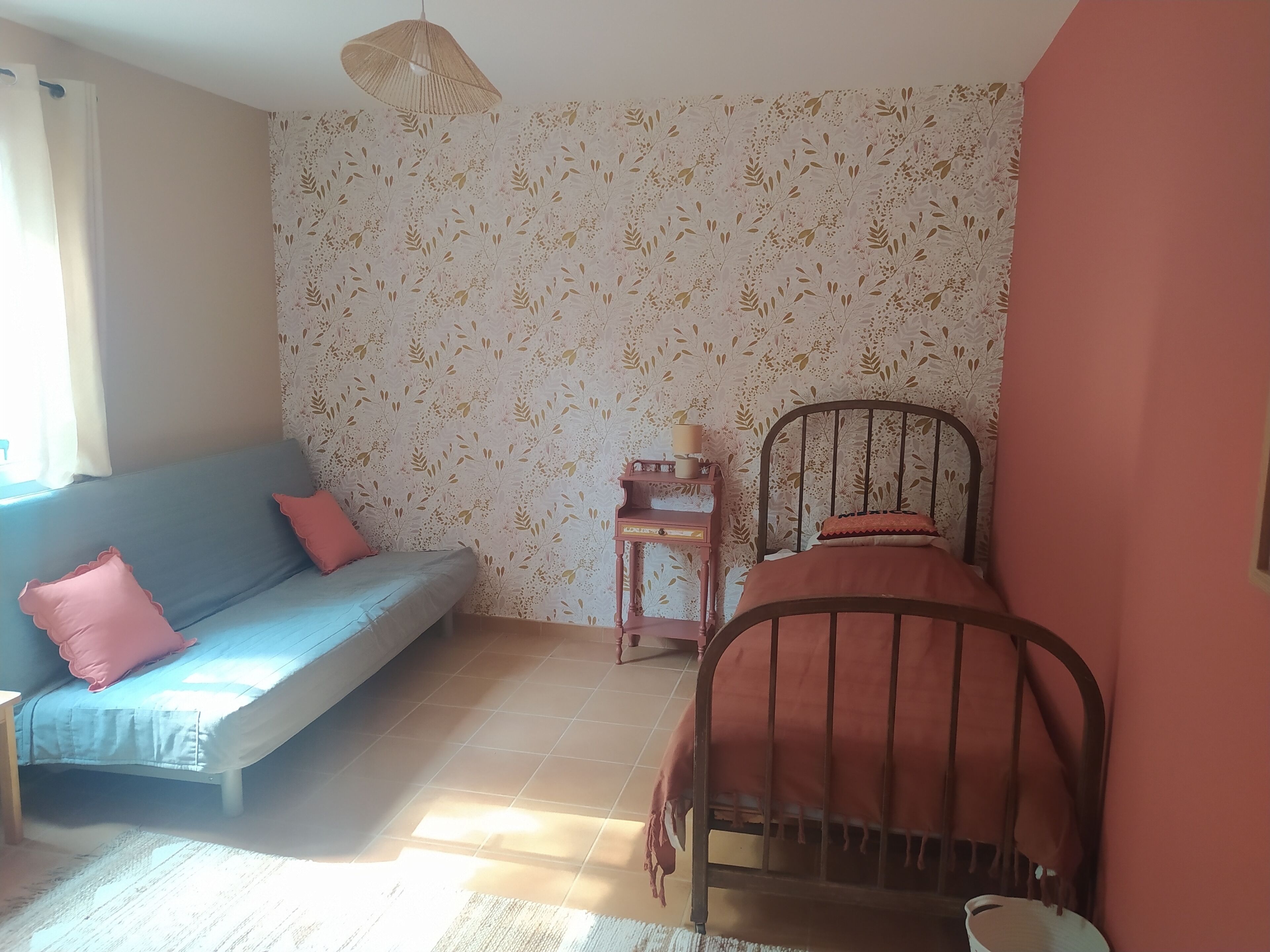 Una habitación con sofá, cama, una mesita y una lámpara colgante.
